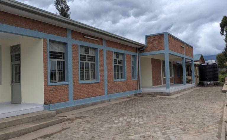 Brick building with blue frame accents and multiple windows along a walkway under a cloudy sky.