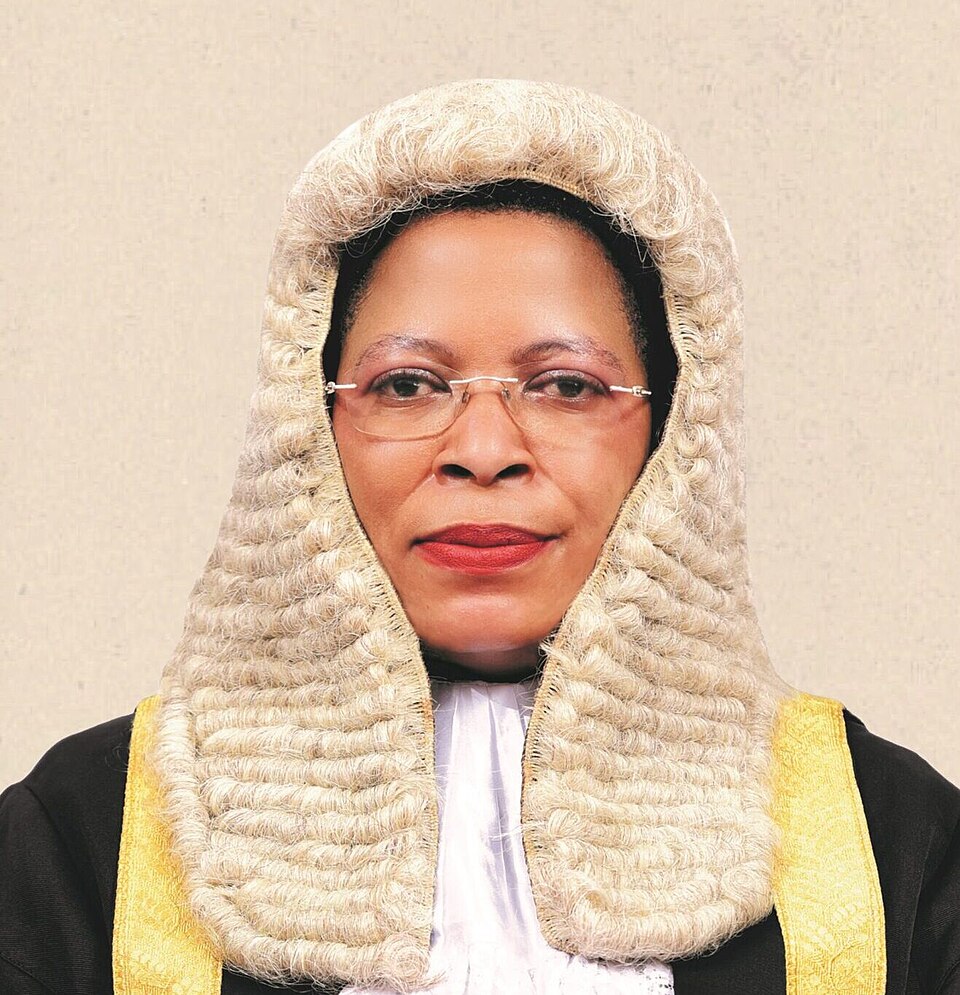 Portrait of a judge in a white powdered wig and ceremonial black robe with gold trim, facing the camera with a calm expression.
