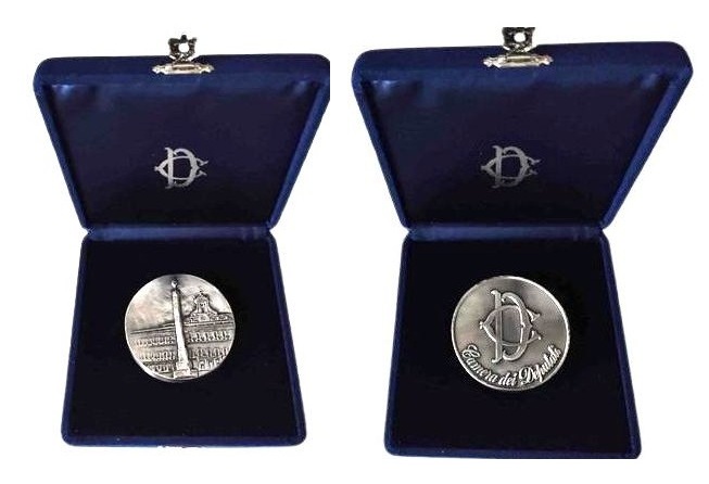 Two silver commemorative coins in blue velvet presentation cases, opened to display each design side by side in white-lined backgrounds.