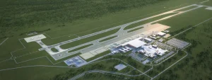 Aerial view of a small airport with runways, taxiways, and a modern terminal complex surrounded by green fields.