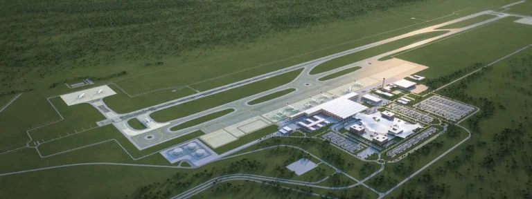 Aerial view of a small airport with runways, taxiways, and a modern terminal complex surrounded by green fields.