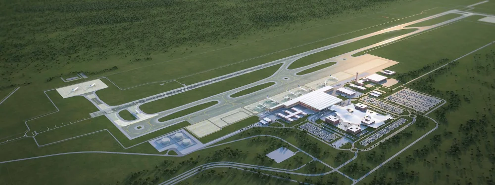 Aerial view of a small airport with runways, taxiways, and a modern terminal complex surrounded by green fields.
