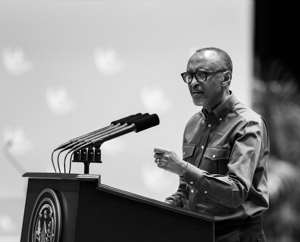 African American man wearing glasses speaking at a podium with multiple microphones at a press conference (black and white).