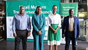 Four professionals stand in a row at a Kigali Modern Tree Nursery Launch, in front of a green event banner.