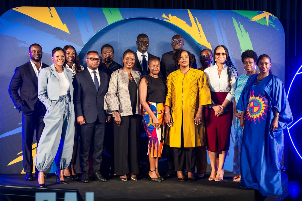 Group of diverse professionals posing on a stage for a formal event backdrop with blue abstract design behind them.