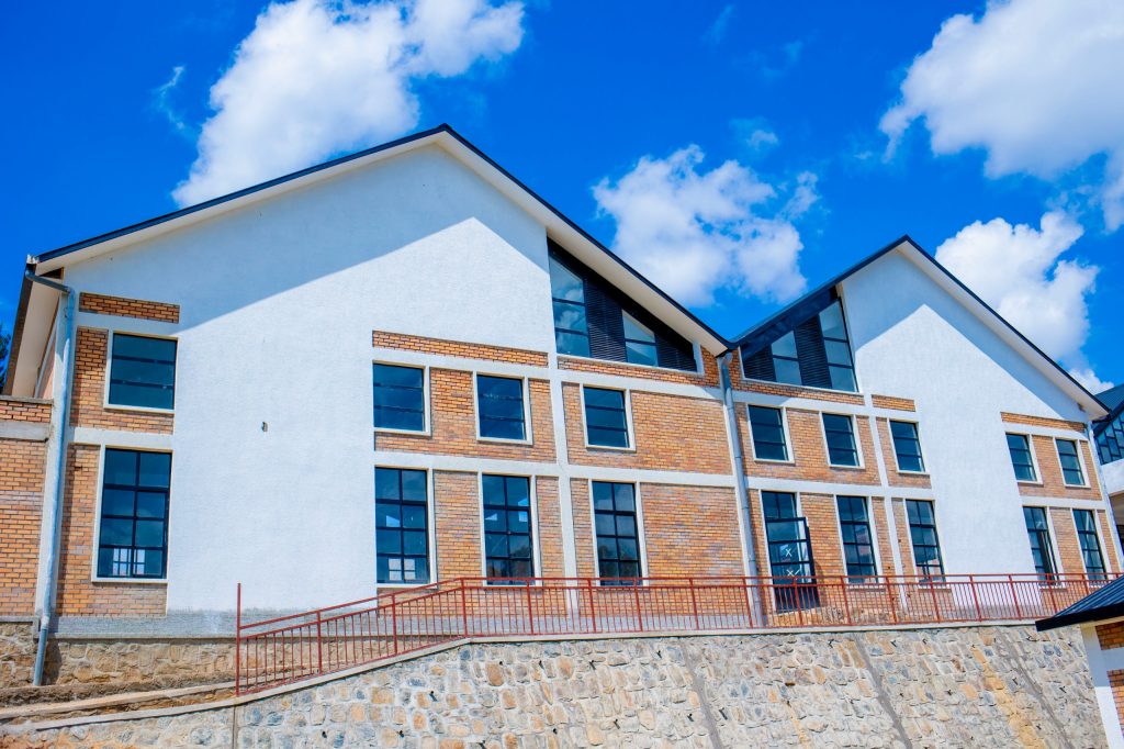 Modern white building with brick accents and large windows under a bright blue sky.