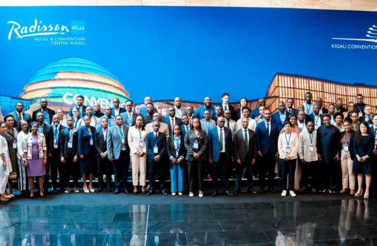 Group of professionals posing for a conference photo in front of a blue Radisson Blu Kigali backdrop.