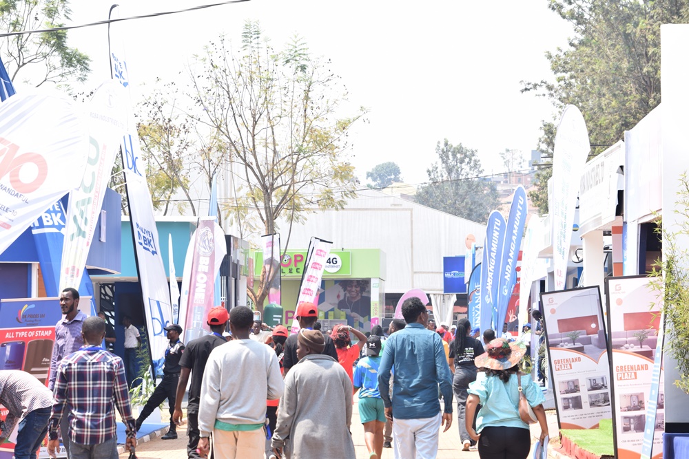 Crowd walking through an outdoor expo with colorful booths, banners, and displays on a sunny day.