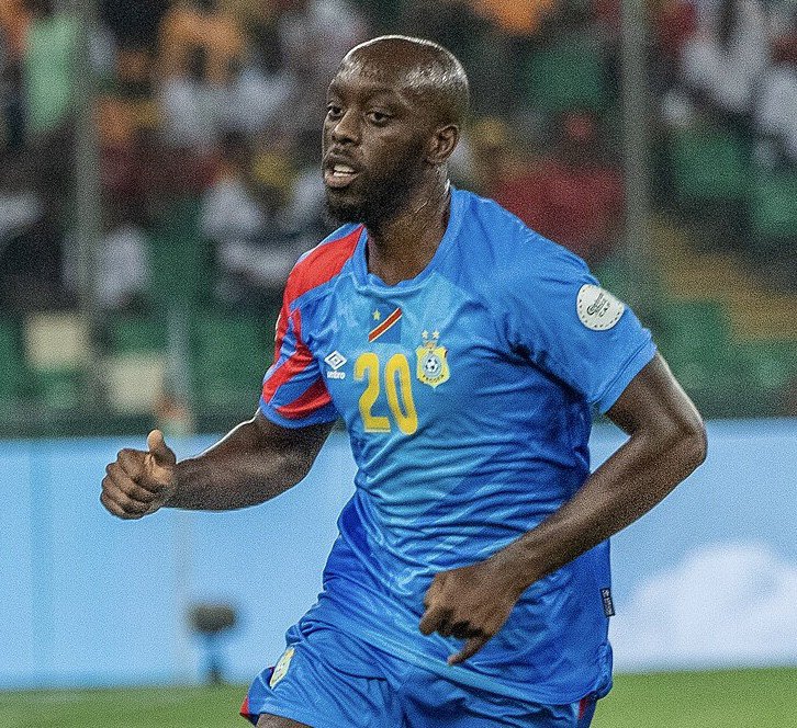 Soccer player in blue jersey with number 20 sprinting on the field during a match, stadium in background