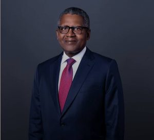 Professional man in a dark suit and pink tie, wearing glasses, posing for a formal portrait against a gray backdrop.