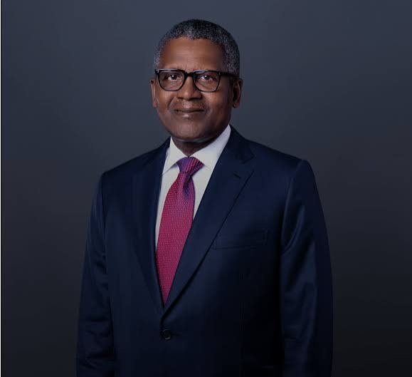 Professional man in a dark suit and pink tie, wearing glasses, posing for a formal portrait against a gray backdrop.