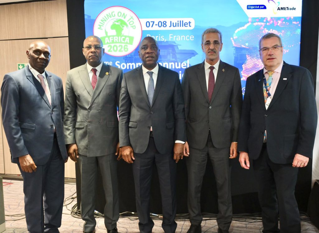 Five men in dark suits pose for a group photo at a mining conference backdrop showing 'MINING ON TOP AFRICA 2026' and 'Paris, France' text.