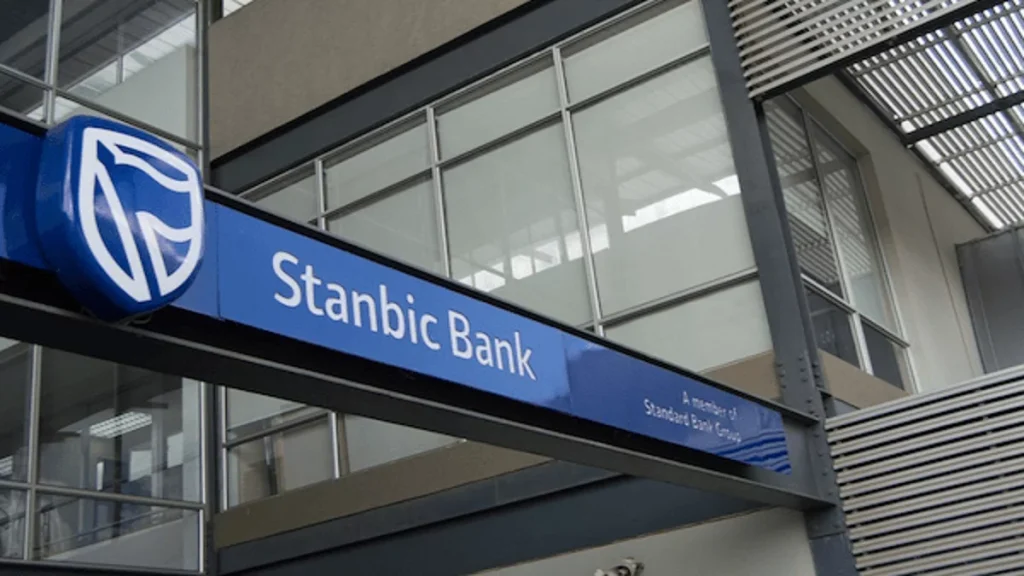 Stanbic Bank storefront sign with blue logo on a modern glass building exterior.