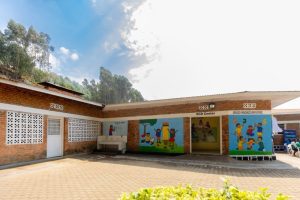 Exterior of a brick school building with colorful murals of children playing outside, and a sign reading 'ECD Center'.